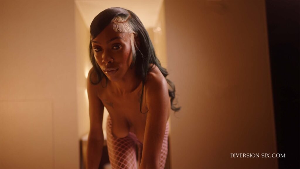 A naked black babe with big tits crawling on a bed in a sexy pose.