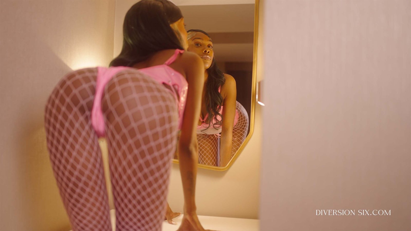 Hot black nude model Dolly D bending over with her showing her nice ass wearing pink fishnet stockings 