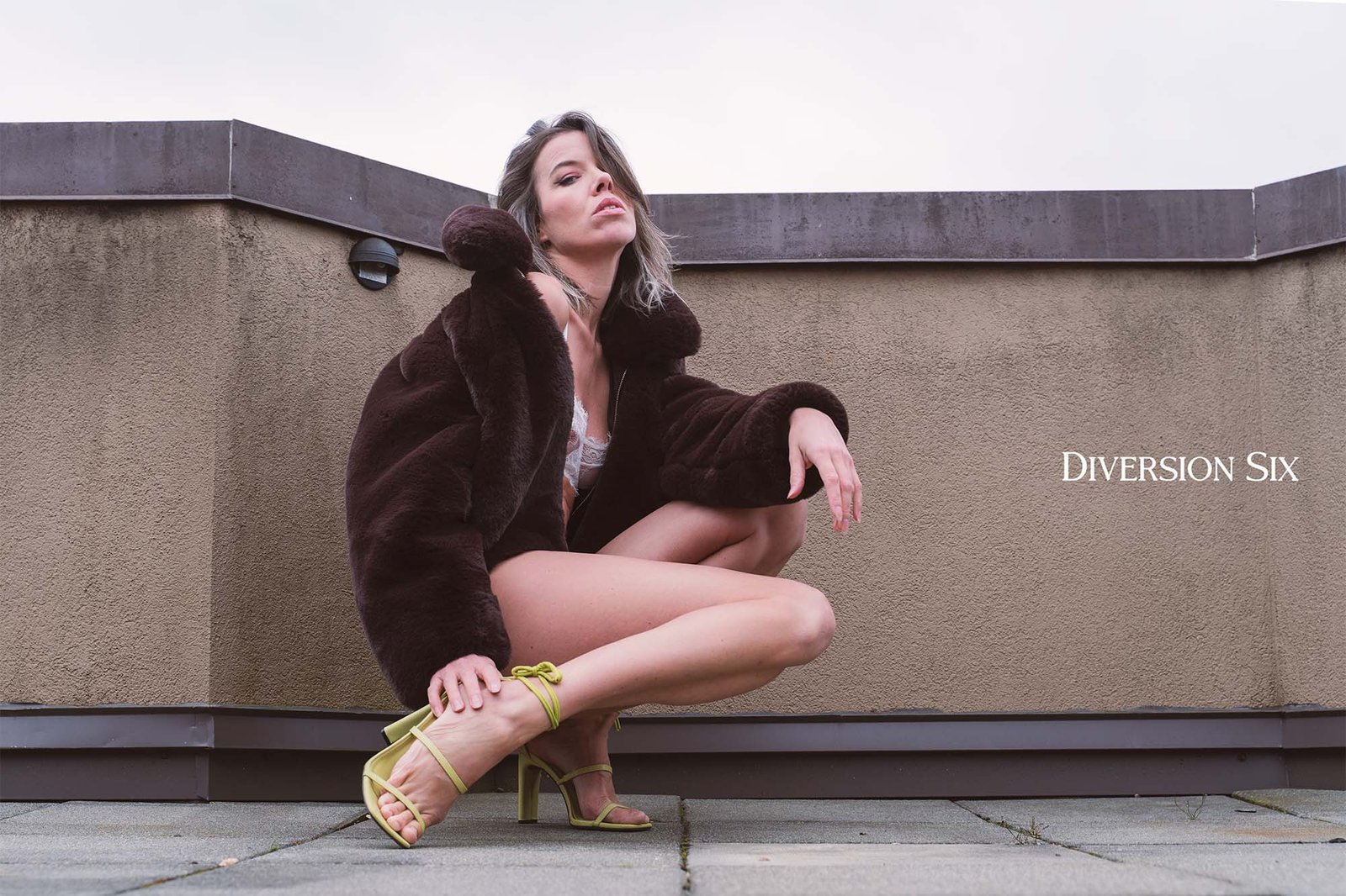 a woman wearing high heels and a fur coat in sitting down in sexy fashion forward pose